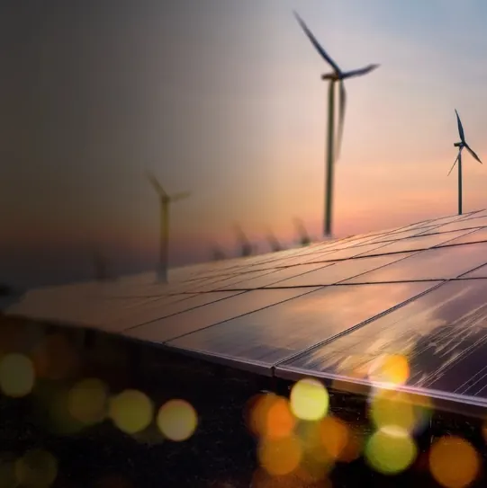 Solar panels and wind turbines at sunset